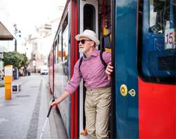 senior man with white cane exiting bus